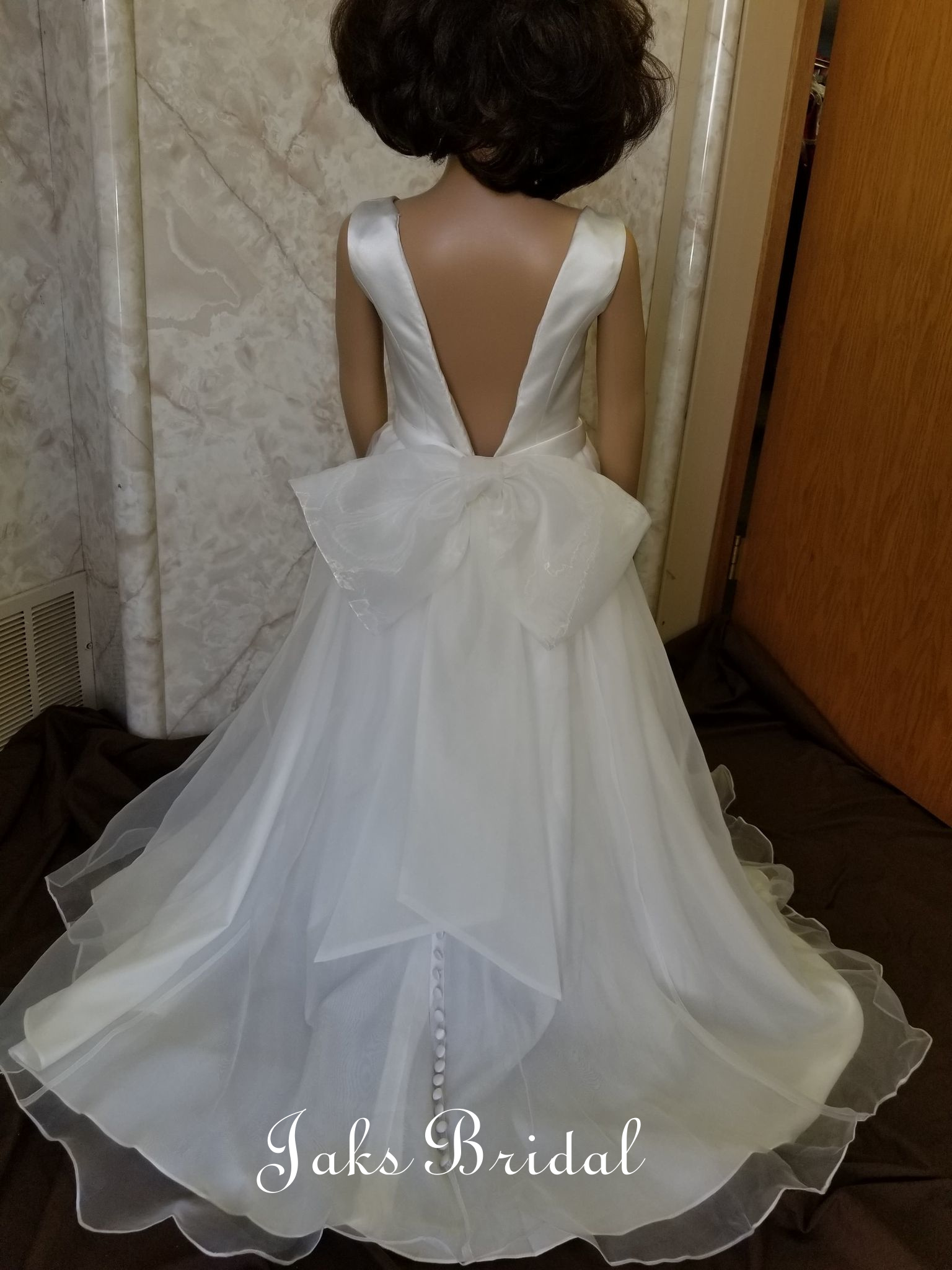 Beautiful organza plunging back flower girl dress with a soft bow waist, and a small train.